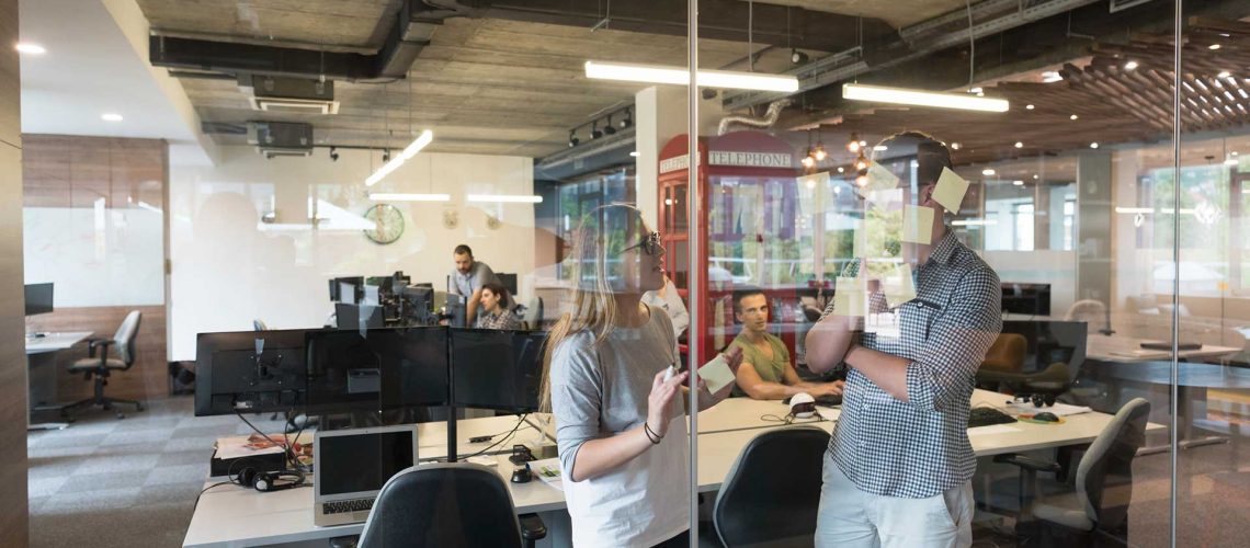 young-couple-at-modern-office-interior-writing-PAABCRB